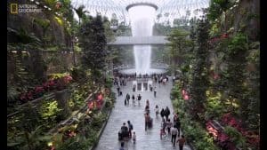 The Rain Vortex waterfall and forest walkway inside Jewel Changi Airport, with travellers on the concourse below
