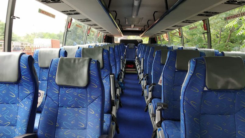 blue fabric bus seats with headrests lined up along the aisle of a charter coach in singapore